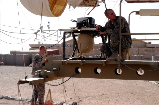 CONTINGENCY OPERATING LOCATION Q-WEST, Iraq - Aerostat crewmember Spc. Steven F. Hahn (right), from Memphis, Tenn., stands by the flying sheave, while fellow crewmember Pfc. William C. Williamson, of Seattle, Wash., kneels on the mooring station...