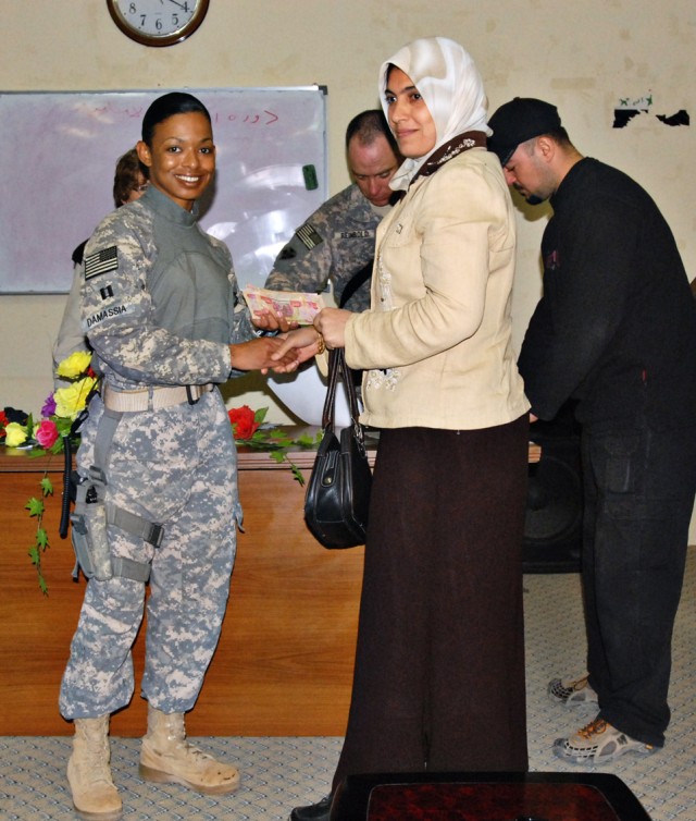 Capt. Kimi Damassia, a Huntington, N.Y. native and liaison officer with the 2nd Brigade Combat Team, 1st Cavalry Division, delivers a micro grant to Dr. Ameera, an Iraqi veterinarian, at the Department of Agriculture in Kirkuk, Iraq, Nov. 17. In...