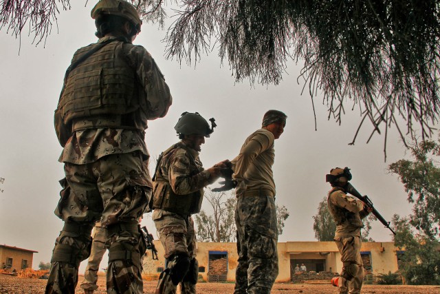 CAMP TAJI, Iraq-Playing the role of a high-value target during a training exercise, Spc. Dale Larrabee (center), from Warsaw, Miss., a joint fires observer from 1st Air Cavalry Brigade, 1st Cavalry Division, gets "detained" by Soldiers from the...
