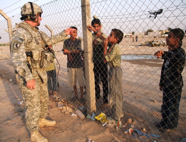 CONTINGENCY OPERATING LOCATION Q-WEST, Iraq - Capt. Drew Clark, a Madison, Miss., native and commander of  A Company, 2nd Battalion, 198th Combined Arms out of Hernando, Miss., chats with local children just outside COB Speicher Nov. 9 during a secur...