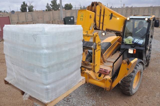Raymond Roehr, a civilian contractor equipment operator and Pasadena, Texas, native takes a pallet of water bottles off of an 1174th Transportation Company, 395th Combat Sustainment Support Battalion, 15th Sustainment Brigade, truck to deliver it...