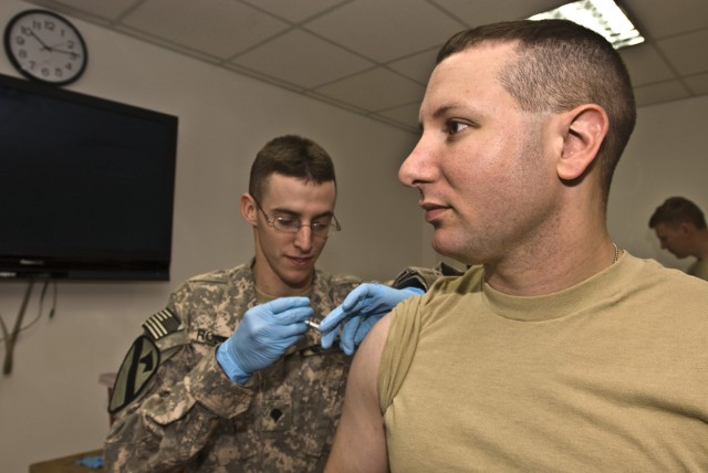 CAMP LIBERTY - Capt. Robert Magill (right), of Buffalo, N.Y., receives the H1N1 flu vaccine from Spc. Justin Roberts, here, Nov. 23. Magill is a military police officer assigned to Company A, Division Special Troops Battalion, 1st Cavalry...