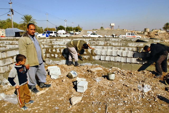 Ali Kamebr Gidan (left), an officer with the 19th Iraqi Army Brigade, and his son, helps a neighbor rebuild his home following a devastating car-bomb attack which killed approximately 90 residents and wounded more than 200 in Taza, Iraq, last...
