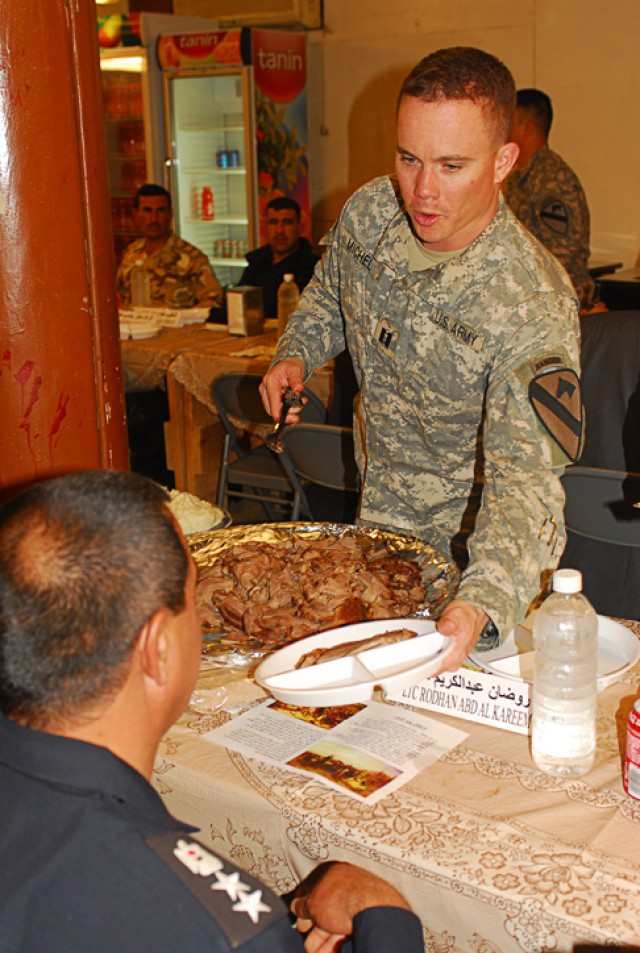 Captain Justin Michel, the commander of Company A, 1st Battalion, 8th Cavalry Regiment, 2nd Brigade Combat Team, 1st Cavalry Division, serves turkey to one of his Iraqi partners during a Thanksgiving meal at Joint Security Station McHenry in Kirkuk p...