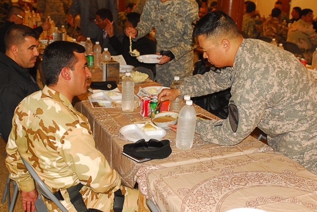 Capt. Eric Hong, the commander of Company B, 1st Battalion, 8th Cavalry Regiment, 2nd Brigade Combat Team, 1st Cavalry Division, ladles gravy onto mashed potatoes for one of his Iraqi partners during a Thanksgiving meal at Joint Security Station McHe...