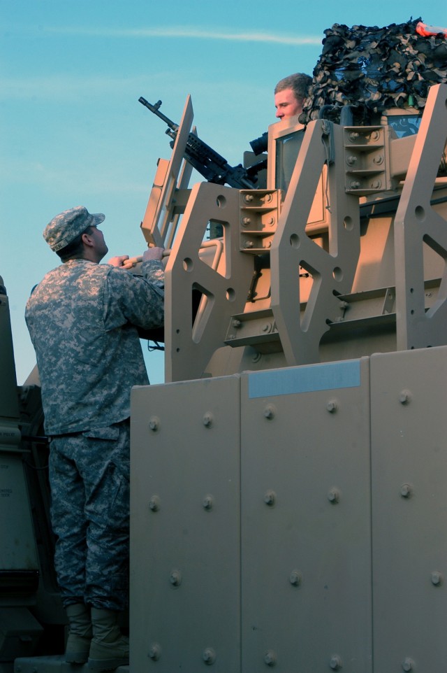 CONTINGENCY OPERATING LOCATION Q-WEST, Iraq - Spc. Todd D. Simpson (standing), a gun truck driver from Cleveland, Miss., speaks with Pfc. Charles E. Hall, III, a gun truck driver who is standing in the gunner's hatch of his Caimen version of the...