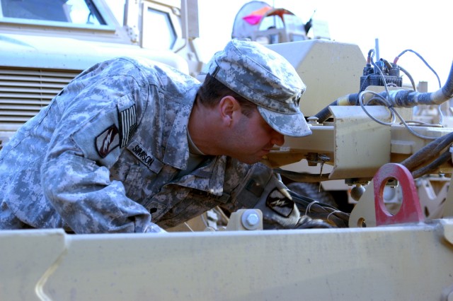 CONTINGENCY OPERATING LOCATION Q-WEST, Iraq - Spc. Todd D. Simpson, a gun truck driver from Cleveland, Miss., inspects the Self-Protection Adaptive Roller Kit attached to the truck's front, absorbing the damage of IEDs and shielding the vehicle...
