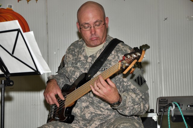 Sgt. 1st Class Eric Cryer, 3rd Infantry Division bandsmen, plays Christmas music on his bass guitar with the 3rd Infantry Division's The Marne Jazz Ensemble in the dining facility here Nov. 26 as part of the Thanksgiving festivities. (U.S. Army...