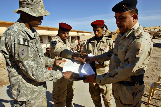 Sergeant First Class Kenya Strong (left), a Miami native and noncommissioned officer in charge of a Military Transition Team, reviews a literacy course curriculum with 2nd Lt. Abeer, an instructor with the 49th Iraqi Army Brigade, 12th IA Division, a...
