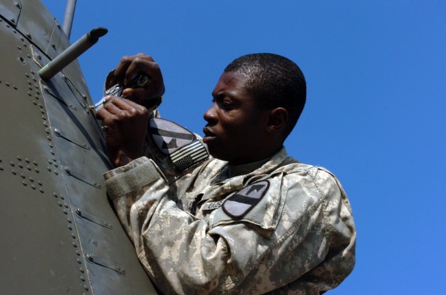 CAMP TAJI, Iraq- Spc. Opeyemi Akinwumi, from Wylie, Texas, a crew chief in Company C, 1st Battalion, 227th Aviation Regiment, 1st Air Cavalry Brigade, 1st Cavalry Division, tightens the panels on the tail of an AH-64D Apache attack helicopter,...