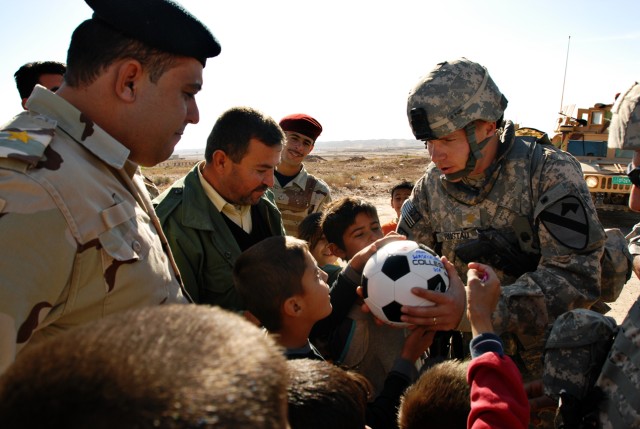 Major Tim Rustad, a Mankato, Minn., native and in charge of the 49th Iraqi Army Brigade Military Transition Team, hands a soccer ball to an Iraqi child near Dibbis in Kirkuk province Iraq, Dec. 3. Soldiers from the MITT began a soccer ball drive dubb...