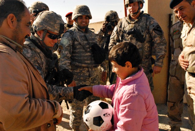 Team, shakes hands with an Iraqi child after handing him a soccer ball near Dibbis in Kirkuk province Iraq, Dec. 3. Soldiers from the MiTT began a soccer-ball drive dubbed "Operation Wild Balls". The soccer-balls were donated from friends, Families a...