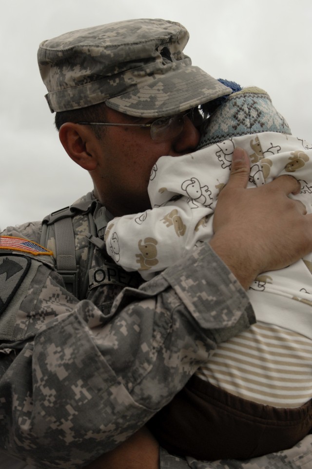 Spc. Cruz Lopez, a medic with 3rd Battalion, 8th Cavalry Regiment, 3rd Heavy Brigade Combat Team, 1st Cavalry Division embraces his son Jaiden on Cooper Field in front of the division's headquarters building. Jaiden was born in July while Lopez...
