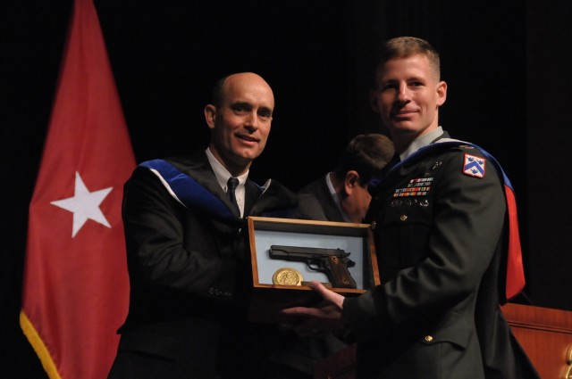 Graduation guest speaker Judge James E. Baker (left), United States Court of Appeals for the Armed Forces, presents Command and General Staff College student and class president Lt. Col. Richard G. Malish with a replica pistol recognizing him as...
