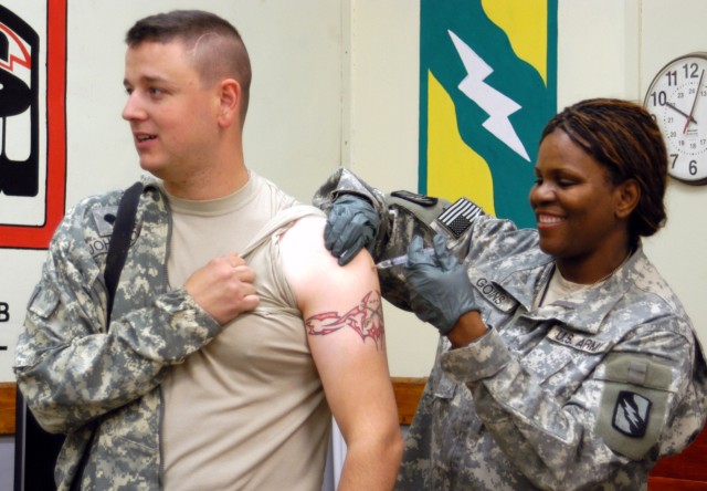 Spc. Jackie L. Johnson, III, a driver with the Quick Reaction Force and a Hernando, Miss., native, receives a vaccination for the H1N1 flu virus from Sgt. Julia R. Goins, a senior medic and a Jackson, Miss., native, Nov. 28 at the base defense...