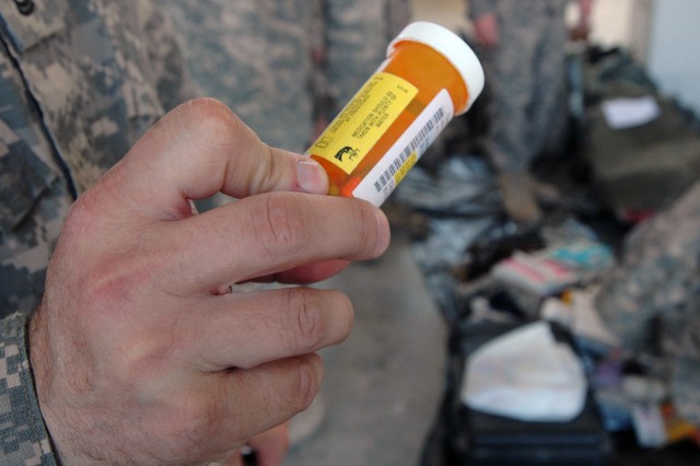 BAGHDAD - Sgt. 1st Class Travis Huggard, the 1st Cavalry Division's customs program manager, reveals a prescription pill bottle found in a Soldier's footlocker that was being inspected to be shipped home, Dec. 11.  All prescription drugs must be...