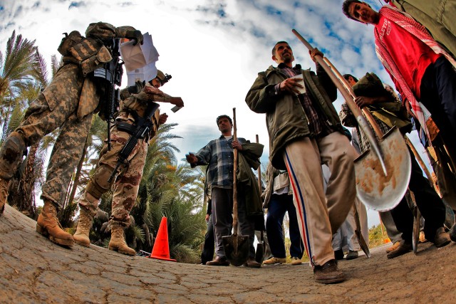 TAJI, Iraq - After taking control of a small intersection, Staff Sgt. Sasaki Palik (left), from Micronesia, a squad leader in 3rd Battalion, 227th Aviation Regiment, 1st Air Cavalry Brigade, 1st Cavalry Division, begins to check the ID cards of perso...