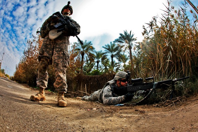 TAJI, Iraq - While local Iraqi ID cards are checked and cars searched, Spc. Sean Kuttner (left) from Jacksonville, Fla., a rifleman, and Pfc. John Cummings from Boise, Idaho, a machine gunner, both with 3rd Battalion, 227th Aviation Regiment, 1st Air...