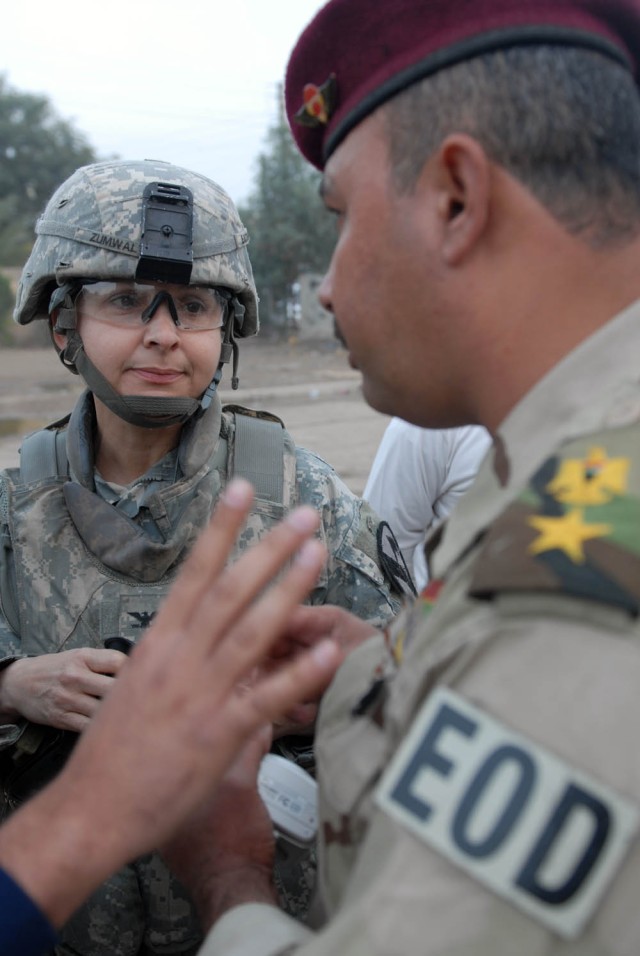 TAJI, Iraq - Bayamon, Puerto Rico native, Col. Maria Zumwalt (left), commander of the 1st Brigade Special Troops Battalion, 1st Brigade Combat Team, 1st Cavalry Division, speaks with Iraqi Lt. Khalid, team leader for the bomb disposal company for the...