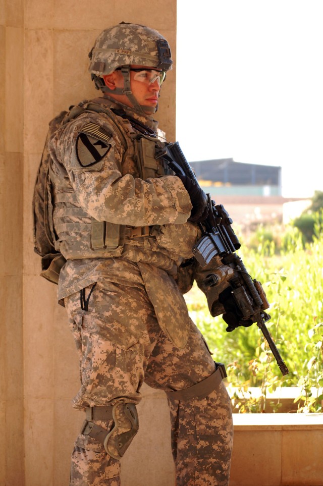 CAMP TAJI, Iraq - Oakdale, N.Y. native, Sgt. Fabrizo Bustos, an armor crewman assigned to Company C, 2nd Battalion, 8th Cavalry Regiment, 1st Brigade Combat Team, 1st Cavalry Division, takes cover behind a pillar while pulling security during a searc...