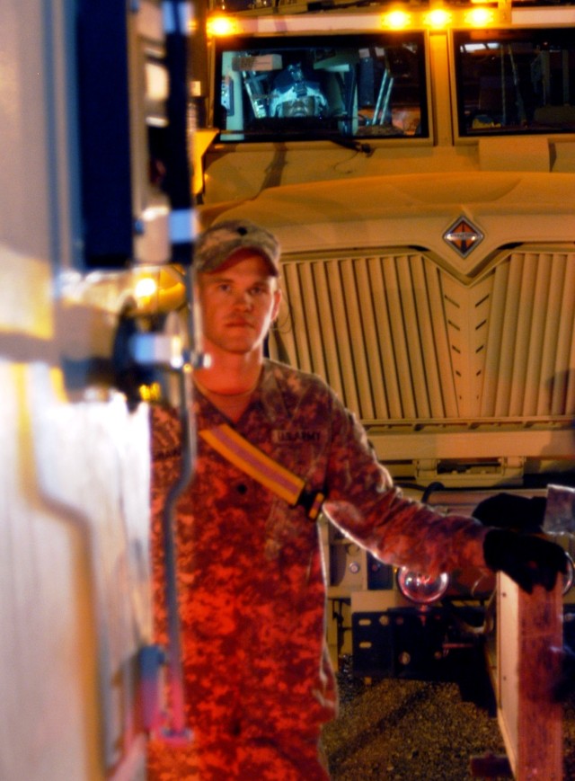 CONTINGENCY OPERATING LOCATION Q-WEST, Iraq - Seen through the rear door of a Mine-Resistant, Ambush-Protected gun truck, Spc. Christopher Shaw, gunner from Taylorsville, Miss., waits in the Convoy Readiness Center yard of Q-West before a convoy...