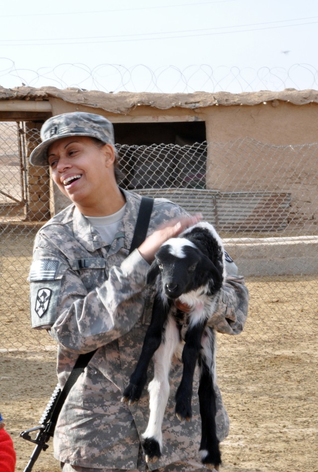 Capt. Elaina Hill, a Fairbanks, Alaska, native, and the 15th Sust. Bde. adjutant, holds a lamb during a visit here by 15th Sust. Bde. leaders Dec. 16. "When [Hussen Ismaiel Ahnd, Jedellah Sofla's mukhtar,] shoved that lamb [at me], he said, 'What's y...