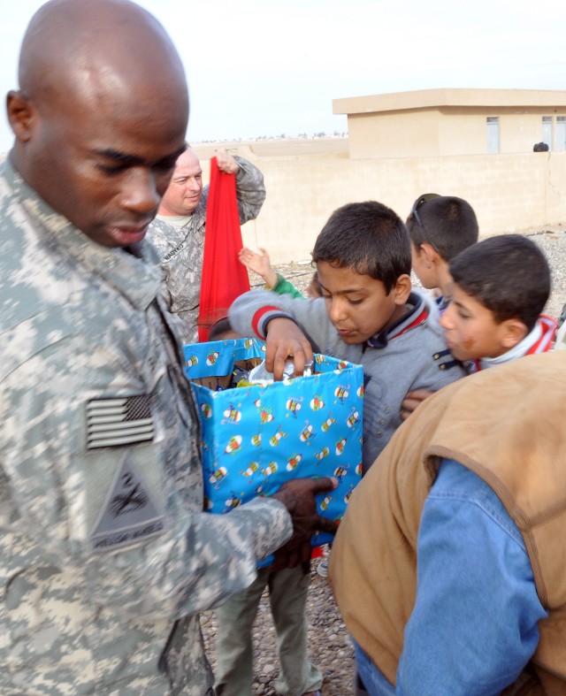 Command Sgt. Maj. Nathaniel Bartee, 15th Sust. Bde.'s senior noncommissioned officer and Quitman, Ga., native, gives gifts to village children during a visit here by 15th Sust. Bde. leaders Dec. 16. (U.S. Army photo by Sgt. Matthew C. Cooley, 15th Su...