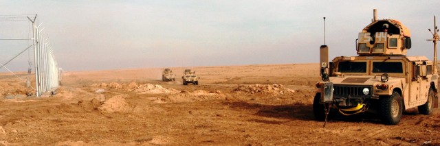 CONTINGENCY OPERATING LOCATION Q-WEST, Iraq - Gun trucks of the force protection company round a corner of the perimeter fence of Contingency Operating Location Q-West during a presence patrol, Dec. 15. The Soldiers serve with the Mississippi Army...