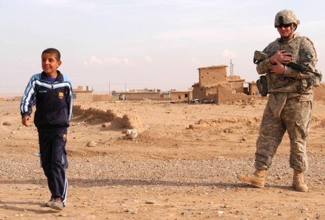 CONTINGENCY OPERATING LOCATION Q-WEST, Iraq -Staff Sgt. Stephen S. Poff (right), a squad leader and truck commander from Ashland, Miss., watches an Iraqi boy in the village of Ejbah who greeted the Soldiers during a presence patrol Dec. 15. The...