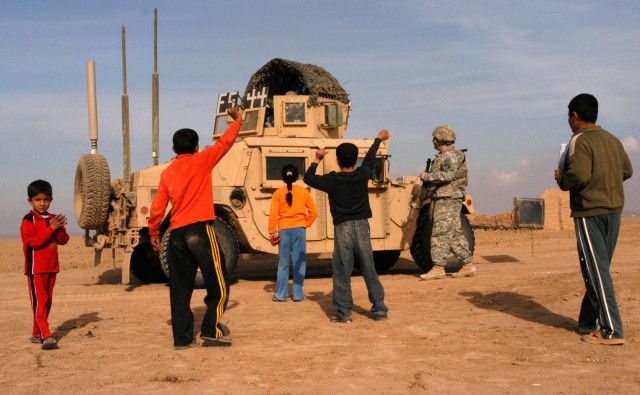 CONTINGENCY OPERATING LOCATION Q-WEST, Iraq - Children of Ejbah, a small village near Contingency Operating Location Q-West, greet members of the base force protection company during a presence patrol Dec. 15. The Soldiers serve with the...