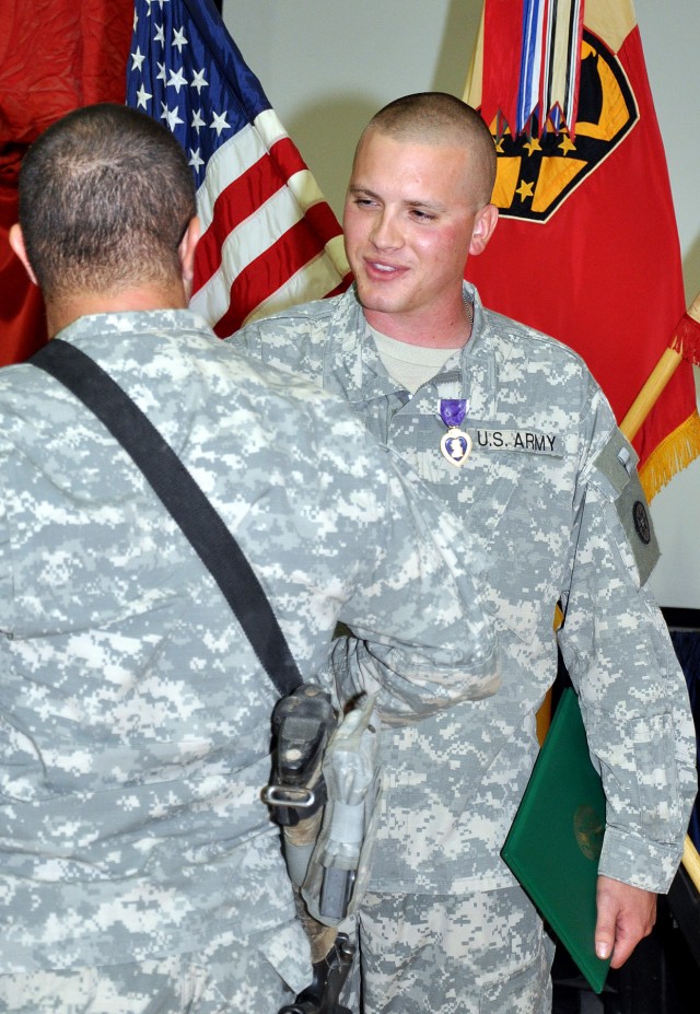 Soldiers congratulate Staff Sgt. Justin Taylor, a Lancaster, Pa., native and assistant platoon sergeant for the 733rd Trans. Co., 395th CSSB stationed in Reading, Pa., after a ceremony awarding him the Purple Heart here Dec. 17 for an injury sustaine...