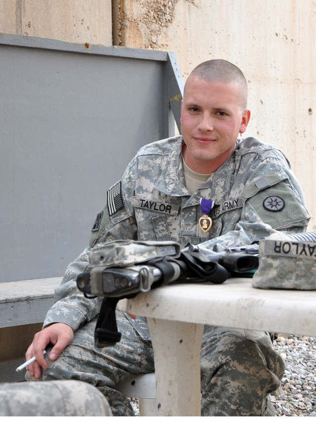 Staff Sgt. Justin Taylor, a Lancaster, Pa., native and assistant platoon sergeant for the 733rd Trans. Co., 395th CSSB stationed in Reading, Pa., wears his newly awarded purple heart while telling war stories to his comrades here, Dec. 17. (U.S. Army...