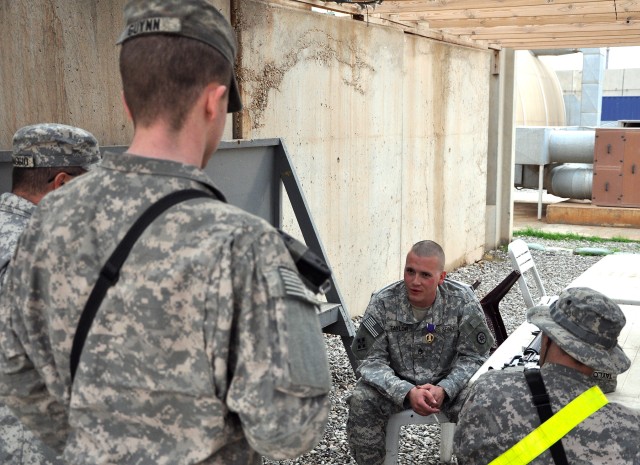 Staff Sgt. Justin Taylor, a Lancaster, Pa., native and assistant platoon sergeant for the 733rd Trans. Co., 395th CSSB stationed in Reading, Pa., wears his newly awarded purple heart while telling war stories to his comrades here, Dec. 17. (U.S. Army...