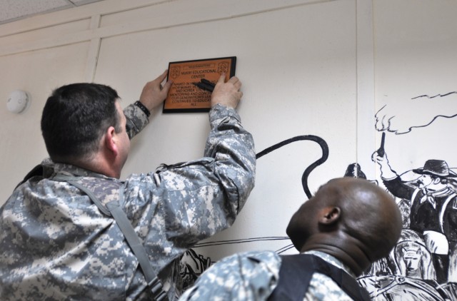 Col. Larry Phelps, the commander of the 15th Sustainment Brigade, hangs the dedication plaque on the wall at the McKay educational center Dec. 31 at Contingency Operating Location Q-West. The center was named for retired Lt. Col. Ivor McKay,...