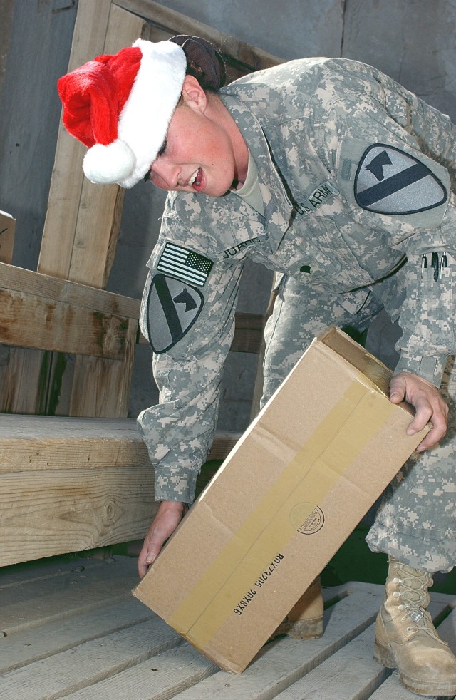 BAGHDAD - Spc. Krystal Juarez, a mail clerk assigned to Company A, Division Special Troops Battalion, 1st Cavalry Division, lifts a Soldier's care package while unloading mail for troops at Camp Liberty, Dec. 23. Juarez, a native of Whiteville, N.C.,...
