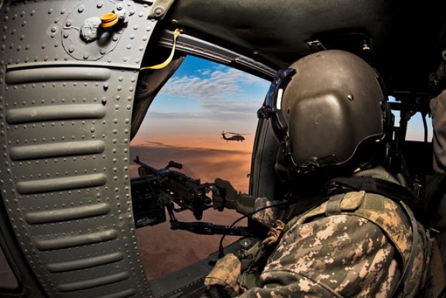 AL ASAD, Iraq - Filling the role of door gunner, Command Sgt. Maj. Glen Vela, from Dallas, the command sergeant major for the 1st Air Cavalry Brigade, 1st Cavalry Division, makes a flight to al-Asad, Iraq, on Christmas Day to visit Soldiers that are ...