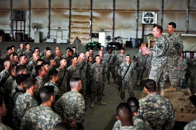 AL ASAD, Iraq - On Christmas Day, Col. Douglas Gabram (left, on stage), from Cleveland, Ohio, the commander of 1st Air Cavalry Brigade, 1st Cavalry Division,  and Command Sgt. Maj. Glen Vela (right, on stage), from Dallas, visit with Soldiers from th...