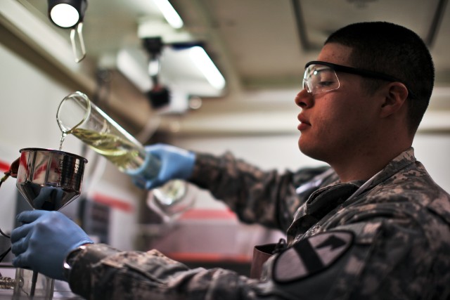 CAMP TAJI, Iraq - To collect any forms of contaminants and sediment, Spc. Juan Rodriguez-Cano, from Edinburg, Texas, a petroleum lab technician, in Company A, 615th Aviation Support Battalion, 1st Air Cavalry Brigade, 1st Cavalry Division, slowly...