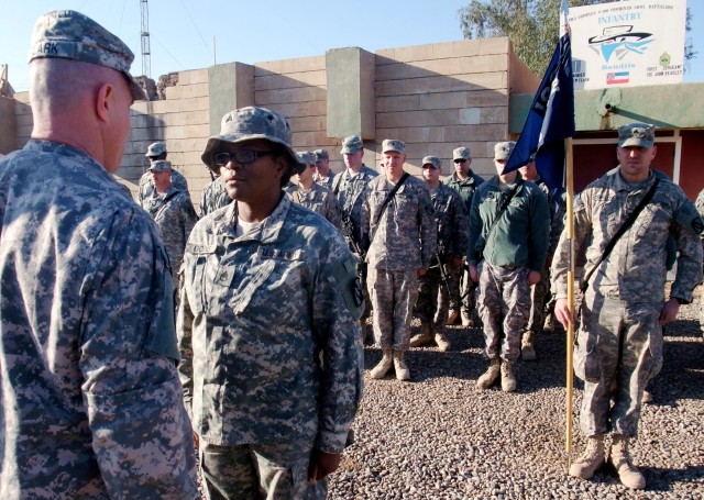 CONTINGENCY OPERATING LOCATION Q-WEST, Iraq - Capt. Drew Clark, a company commander from Madison, Miss., promotes Sgt. Julia R. Goins, a senior medic and native of Jackson, Miss., to staff sergeant during a promotion ceremony in the company area...