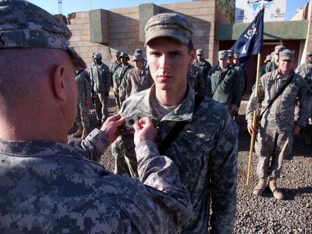 CONTINGENCY OPERATING LOCATION Q-WEST, Iraq - Capt. Drew Clark, a company commander from Madison, Miss., places specialist rank on Pfc. Michael Murtagh, an entry control point guard from Pickens, Miss., during a promotion ceremony in the company...