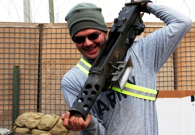 CONTINGENCY OPERATING LOCATION Q-WEST, Iraq - Sgt. Clarence M. Myers, a supply noncommissioned officer in charge from Carrollton, Miss., lugs a .50 cal. machine gun into a packing crate in the company area at Contingency Operating Location Q-West,...