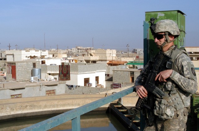 CONTINGENCY OPERATING LOCATION Q-WEST, Iraq - Staff Sgt. Jonathan C. Love, a squad leader from Southaven, Miss., scans the rooftops of Al-Qayyarah during a visit to the filtration plant pumping water to Contingency Operating Location Q-West, Dec....