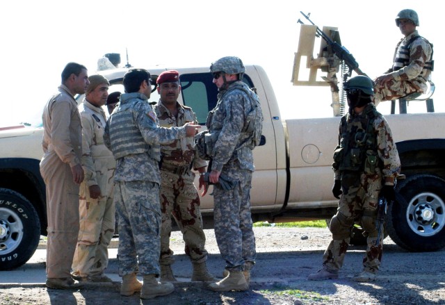 CONTINGENCY OPERATING LOCATION Q-WEST, Iraq - Capt. Drew Clark (center, with gloves), commander of A Company, 2nd Battalion, 198th Combined Arms from Hernando, Miss., speaks through his interpreter to Iraqi Army 1st Lt. Salah Joad (facing, in...
