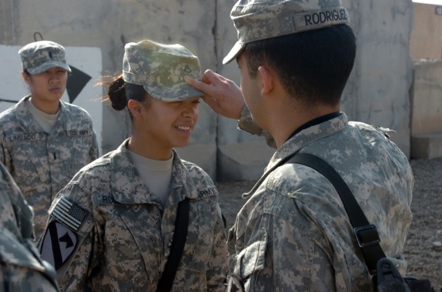 CAMP TAJI, Iraq -  Pfc. Harmony Rodriguez (left), from Victoria, Texas, a cook in Company E, 4th Battalion, 227th Aviation Regiment, 1st Air Cavalry Brigade, 1st Cavalry Division, smiles as her brother, Spc. Jeremiah Rodriguez pins private first clas...