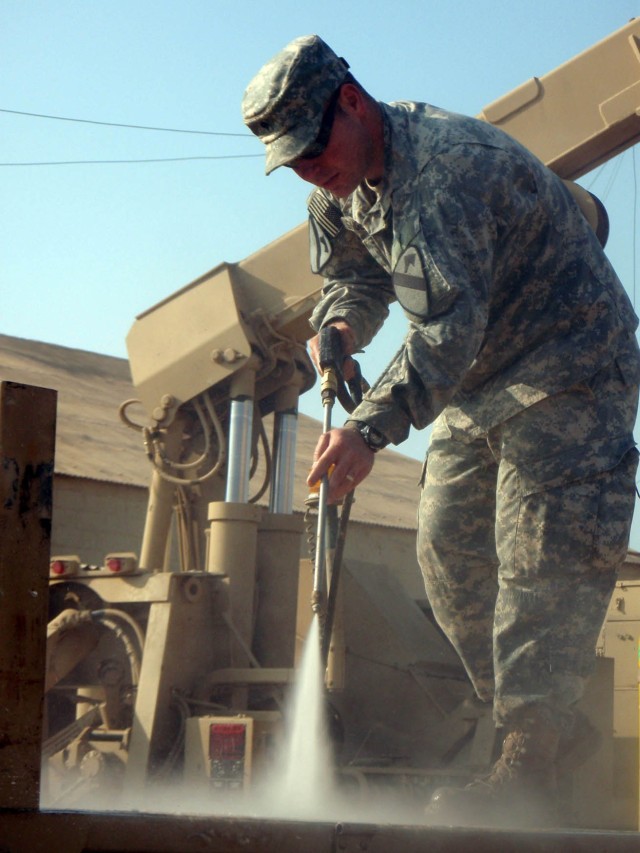 CAMP TAJI, Iraq - Brazoria, Texas native Spc. William Singletary, a welder assigned to Company B, 115th Brigade Support Battalion, 1st Brigade Combat Team, 1st Cavalry Division, uses a pressure washer to clean the flatbed of a palletized load...