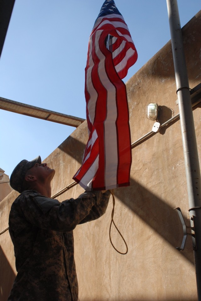 BAGHDAD, Iraq - Wichita, Kan., native, 1st Lt. Ryan Zeller, an infantry officer assigned to Headquarters and Headquarters Company, 1st Brigade Special Troops Battalion, 1st Brigade Combat Team, 1st Cavalry Division, raises a flag during a visit with ...