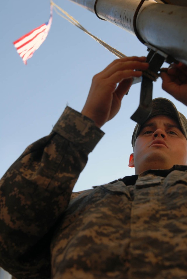 BAGHDAD, Iraq - Wichita, Kan., native Sgt. Kyle Zeller, an infantry team leader assigned to the 2nd Battalion, 7th Infantry Regiment, 1st Brigade Combat Team, 3rd Infantry Division, secures the flag to the pole during a visit with his brother 1st Lt....