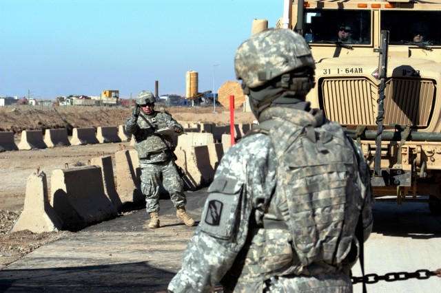 CONTINGENCY OPERATING LOCATION Q-WEST, Iraq - Spc. Ryan E. Ohlendorf (left, distance), a gate sentinel from Horn Lake, Miss., gives a signal for fellow sentinel Pfc. Quintavis B. Byrd, a native of Tutwiler, Miss., to open the gate at the main entry c...