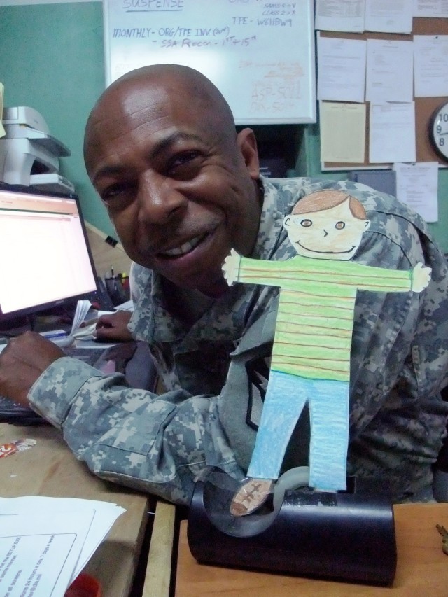 CONTINGENCY OPERATING LOCATION Q-WEST, Iraq - Staff Sgt. Roderick N. Holmes, a supply sergeant from Hernando, Miss., poses in his office at Contingency Operating Location Q-West Jan. 13 with "Flat Stanley," a paper doll used in a pen-pal program. Thi...
