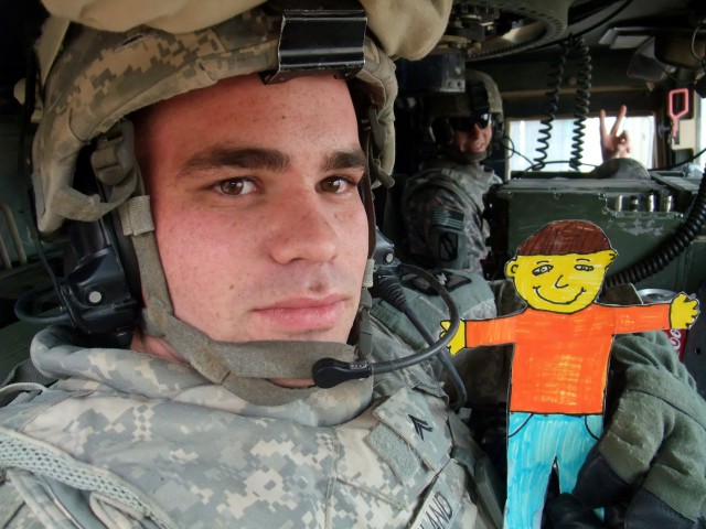CONTINGENCY OPERATING LOCATION Q-WEST, Iraq - Cpl. Justin R. Strickland, a truck commander from Memphis, Tenn., poses in at Contingency Operating Location Q-West Jan. 13 with "Flat Stanley," a paper doll used in a pen-pal program. Third-graders...